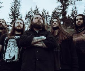 The Black Dahlia Murder photographed in casual attire standing against a backdrop of a forrest on an overcast day 