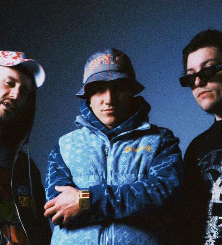 Ocean Grove photographed in front of a blue backdrop, they are all wearing casual attire and Dale is wearing a bucket hat. 